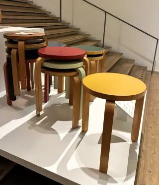 Colourful Aalto stools, including nested stacks, stand on a display platform beside a staircase at Millesgården.