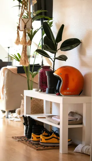 White open hallway shelving with boots and trainers underneath, and a helmet and plants on top.
