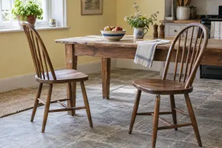 Wooden bow-back kitchen chairs with stick backs beside a dining table.