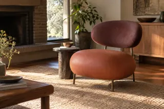 A rounded upholstered lounge chair stands beside a low table in a quiet room.