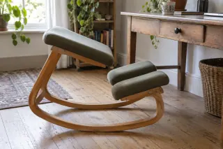 A wooden kneeling chair with a sloping seat and two lower pads at a desk.