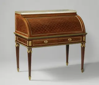 A mahogany cylinder-top desk with a pale marble slab above its curved writing cabinet.