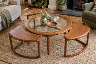 A round glass-top wooden table with three smaller curved tables spread around it.