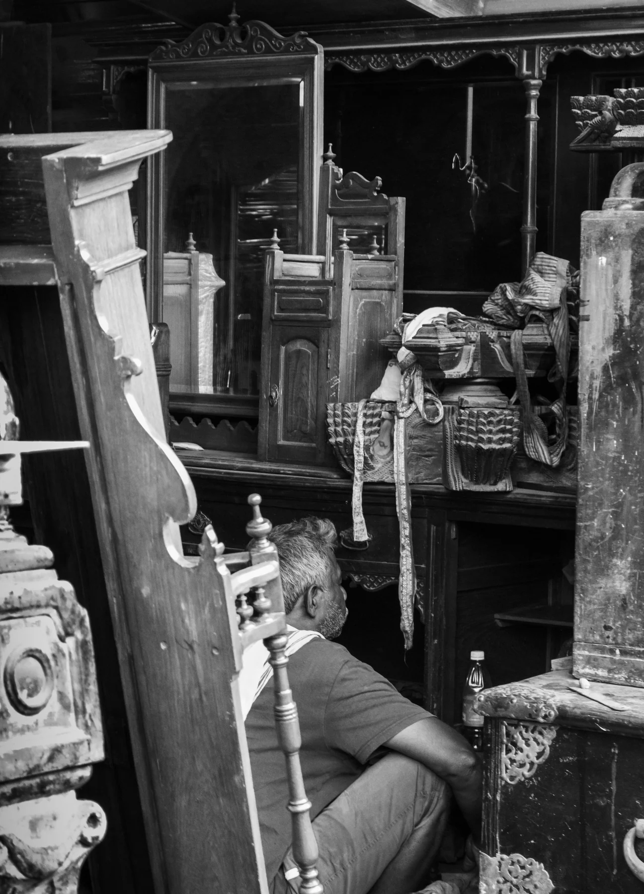 Crowded black-and-white antique shop view with mirrors, chairs and decorated furniture overlapping.