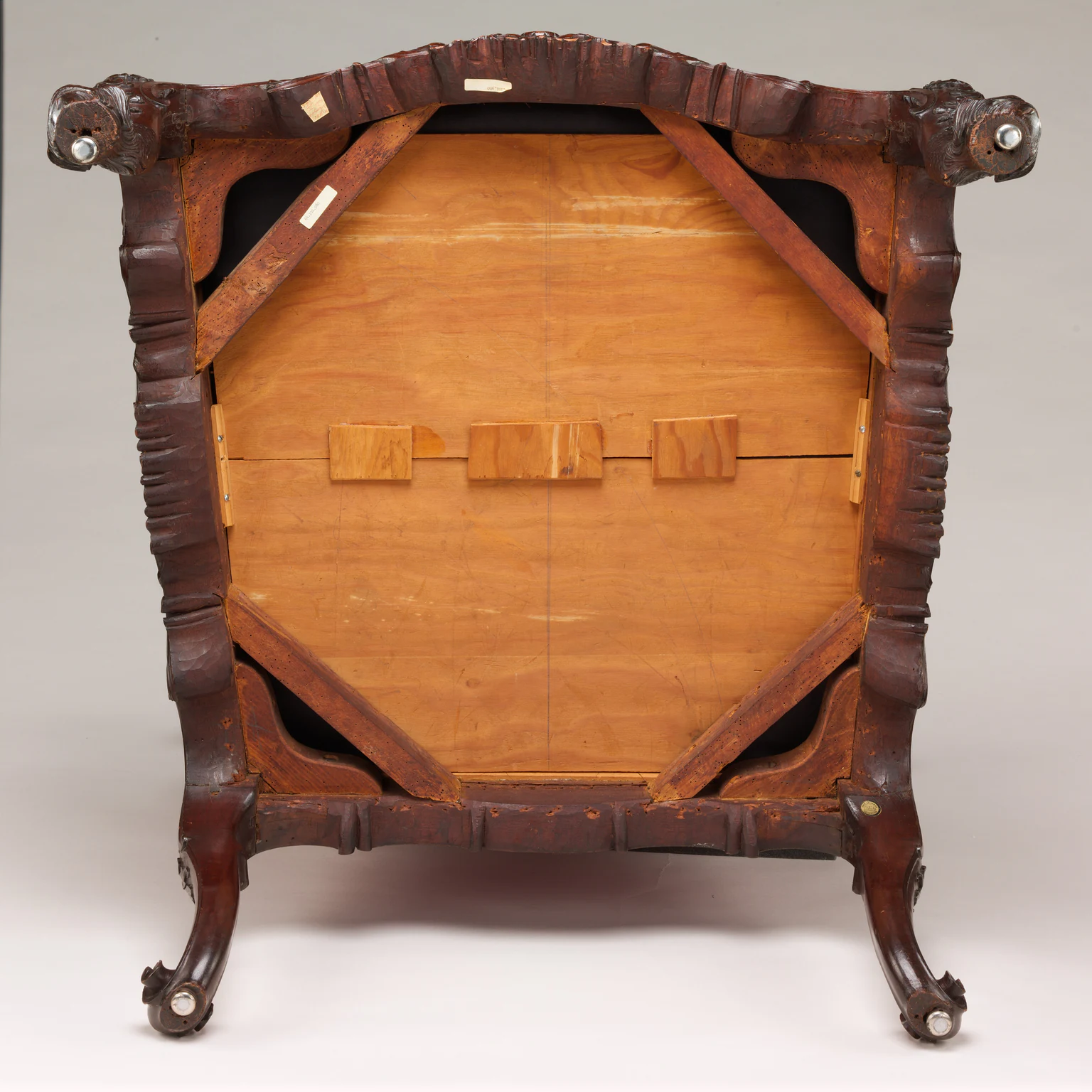 The square underside of the same Met armchair shows its wooden frame, diagonal braces, large central panel, feet and small labels.