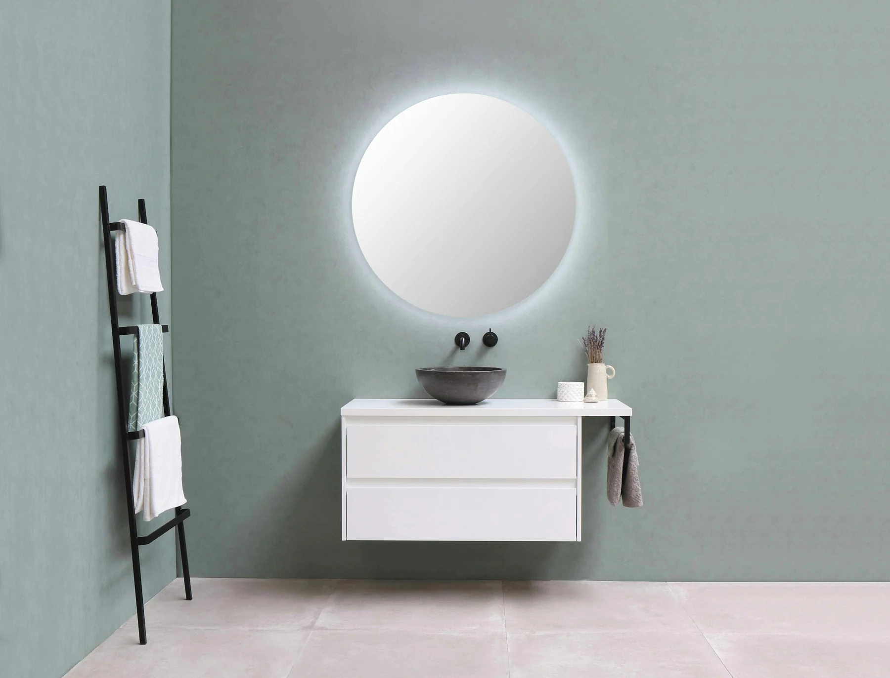 Raised dark bowl basin on a white wall-hung bathroom cabinet, with wall-mounted taps and a round mirror.