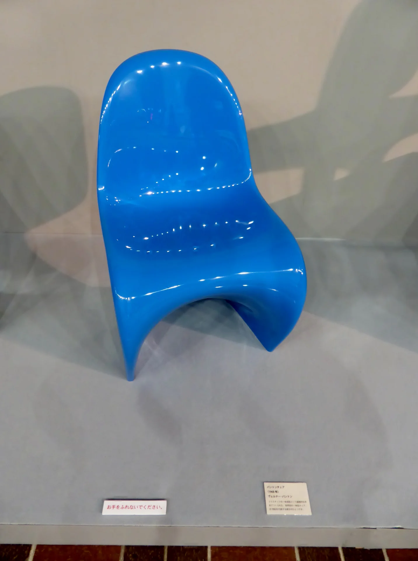 A blue cantilevered Panton Chair shown as a complete object in a museum display.