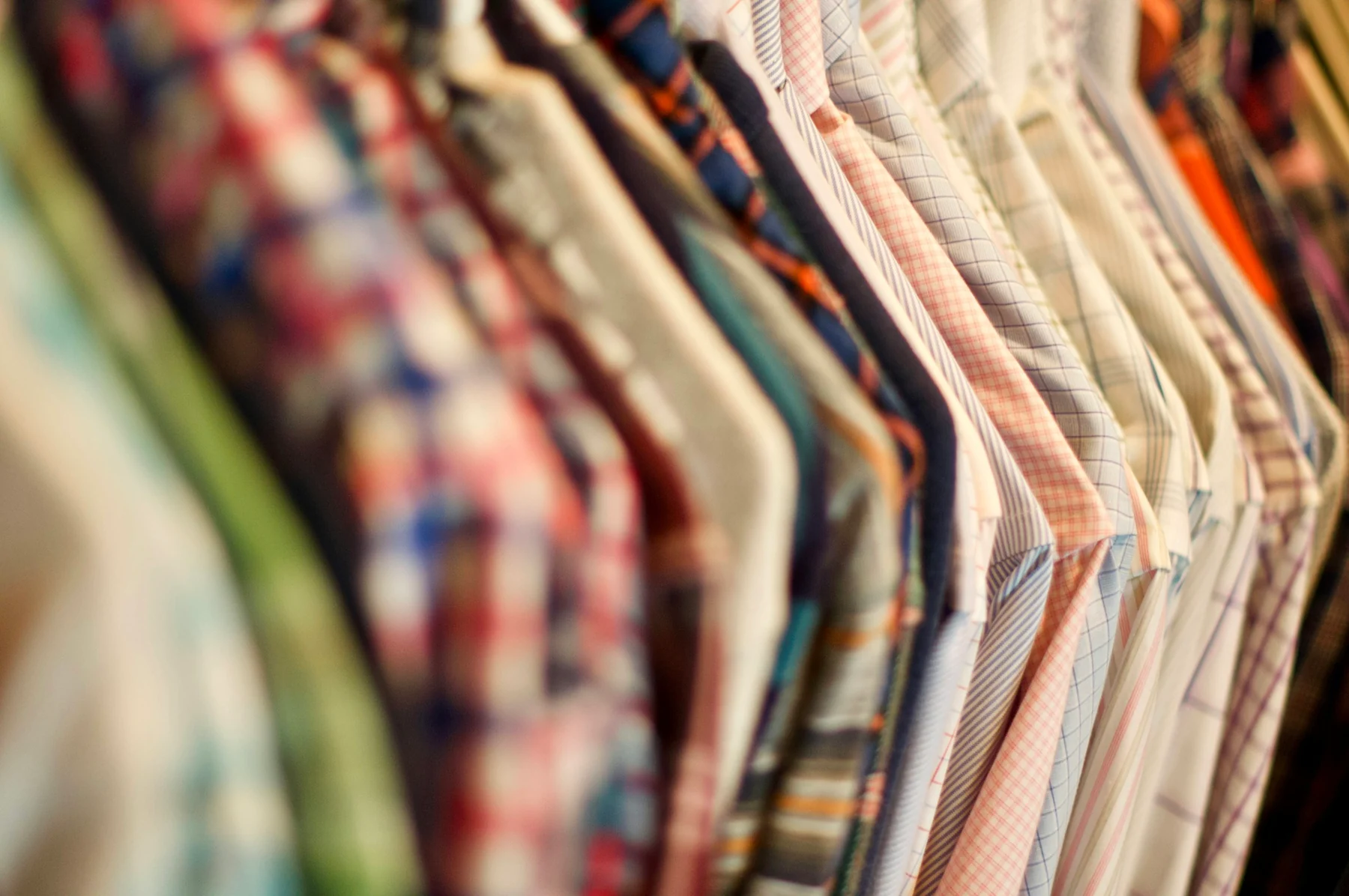 Closely spaced patterned shirts hanging side by side on a clothes rail.